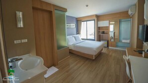 Una habitación de hotel moderna con cama, baño con lavamanos, una mesita pequeña y televisión.