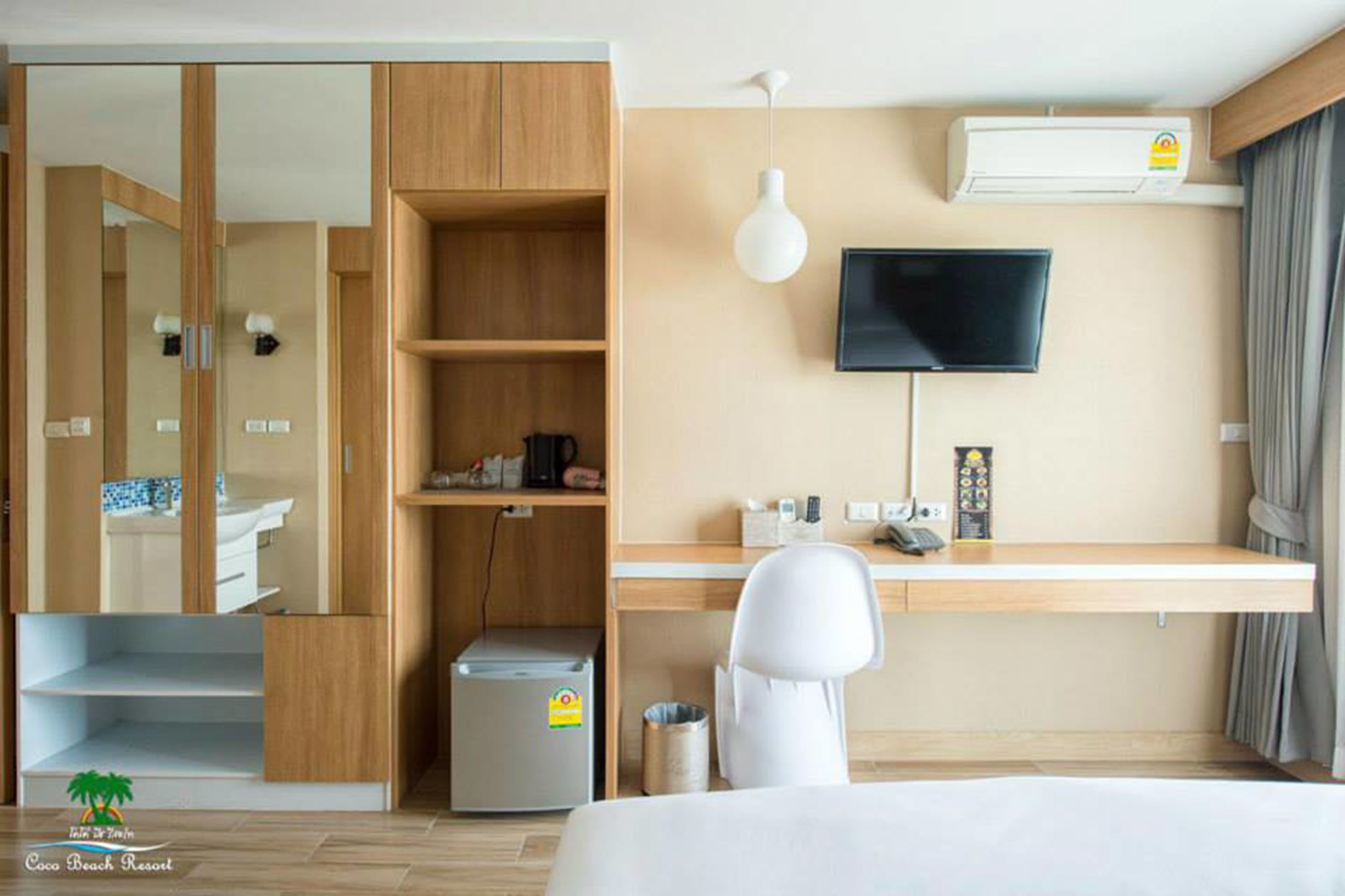 A hotel room with a bed, a desk, a TV, a wardrobe, and a small kitchenette.