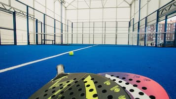 Una palestra coperta con campo da tennis, pavimento blu e linee di delimitazione bianche.