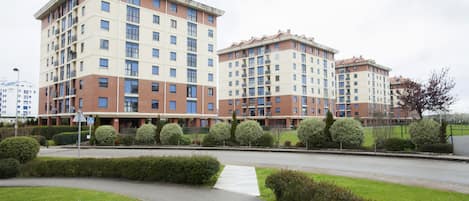 A multi-story residential building with a brick facade, multiple balconies, and a gated entrance.