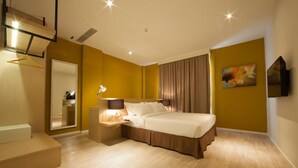 A modern hotel room with a bed, bedside table, lamp, and a large mirror.