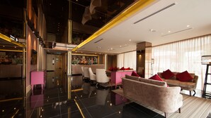 A modern hotel lobby with a spacious layout, a central seating area, and a high ceiling with unique lighting fixtures.