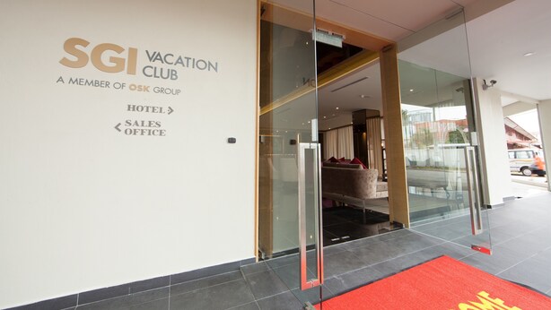 The entrance to the SGI Vacation Club hotel, featuring a glass door, a red carpet, and a sign indicating the hotel, sales, and office areas.
