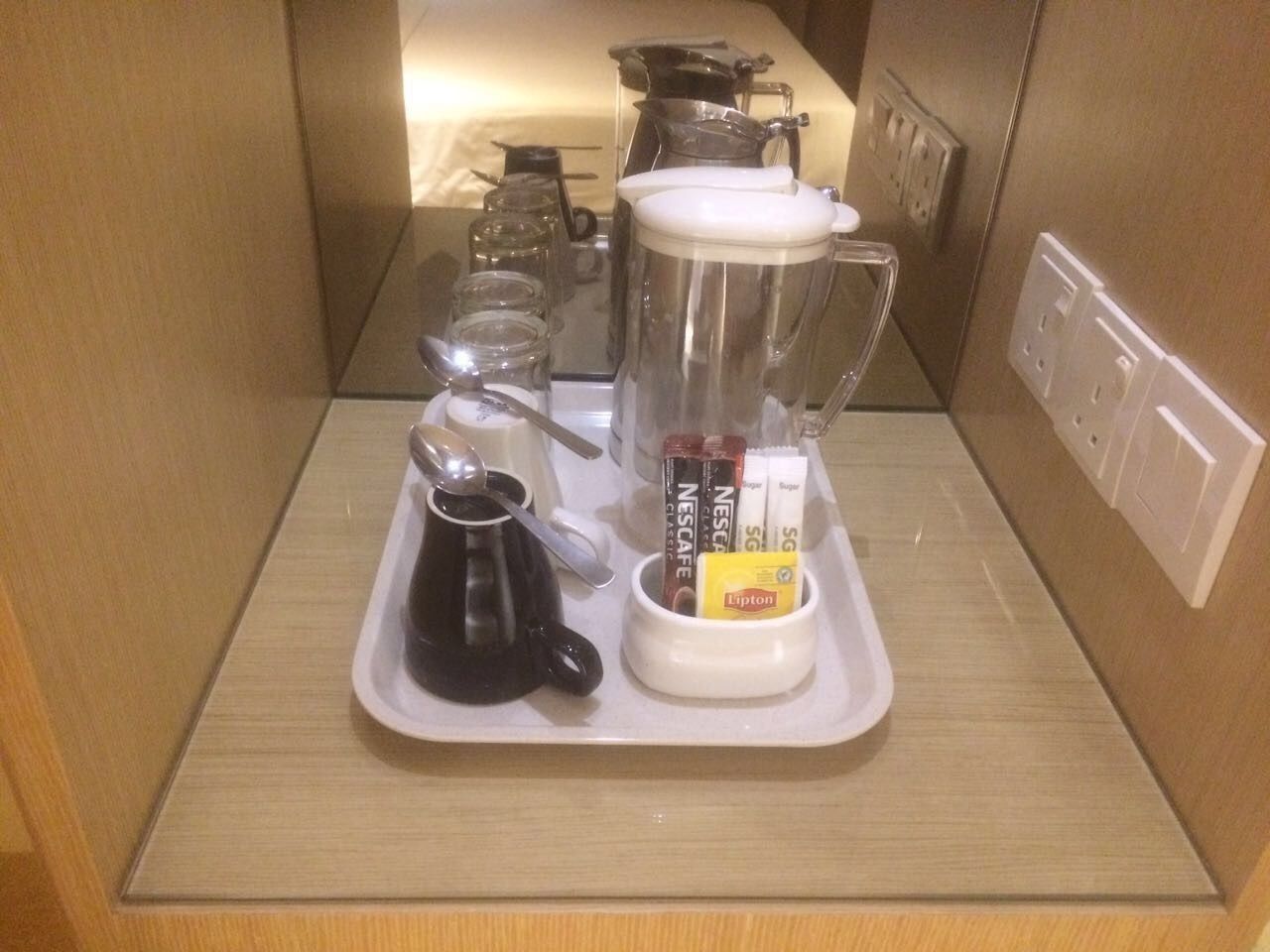 Une petite cuisine équipée d’une machine à café, d’un mixeur et de capsules de café présentées sur un plateau.