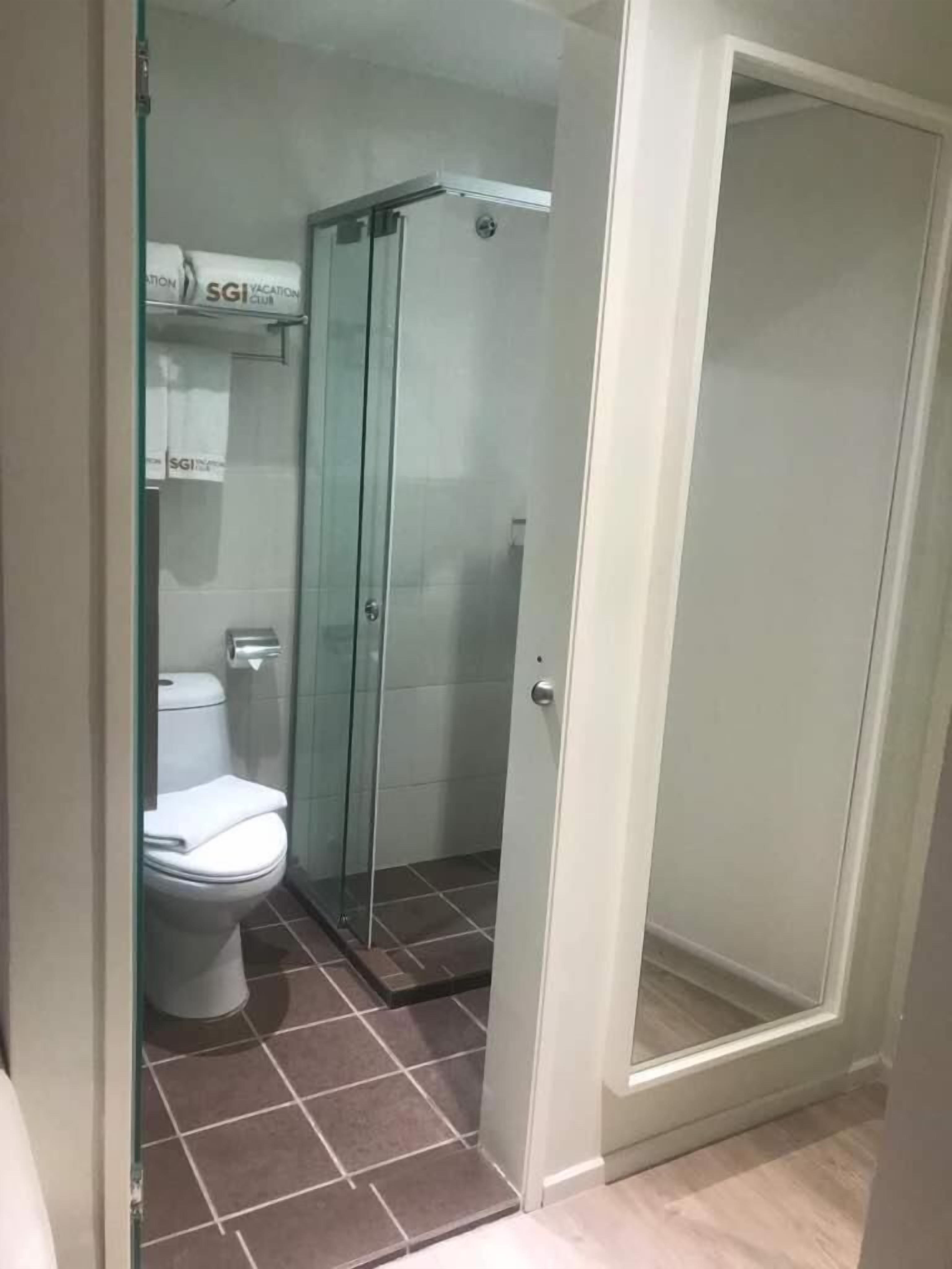 Une salle de bain avec une douche à parois de verre, des toilettes et une étagère avec des serviettes.