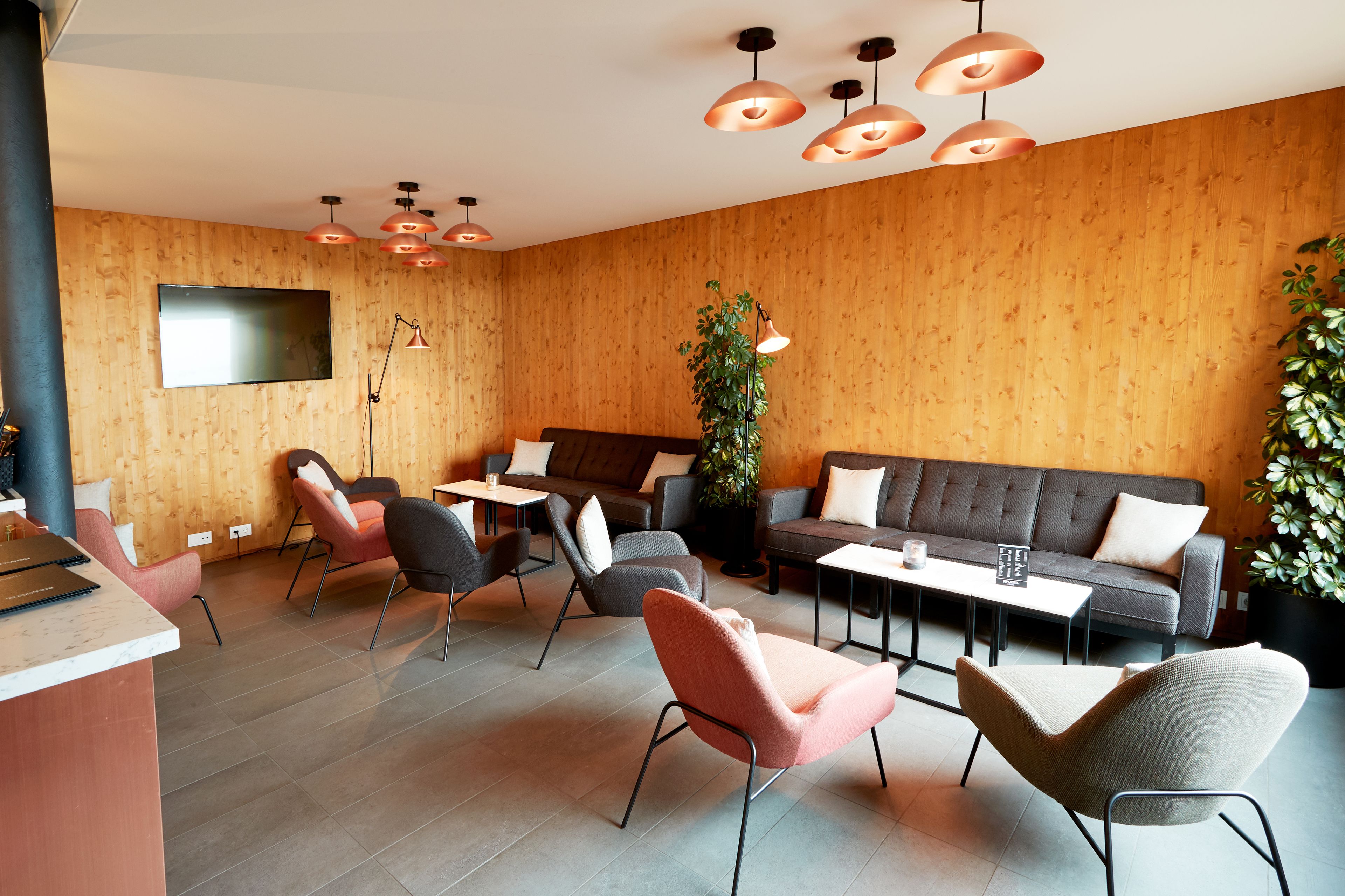 A modern lounge area with a sofa, chairs, a coffee table, and a TV mounted on the wall.