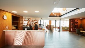 A modern reception area with a wooden reception desk, a clock, and a seating area with sofas and chairs. - Fosshotel Myvatn (Myvatn)