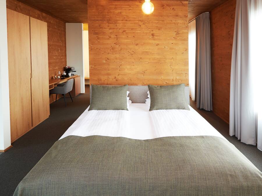 A hotel room with a large bed, a desk, and a chair.