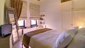 Een slaapkamer met een bed, een televisie, een kledingkast en een raam met gordijnen.