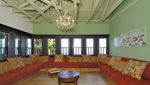 Een ruime kamer met een grote houten bank, een houten salontafel en een kroonluchter.