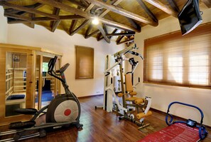 Gimnasio con una máquina elíptica, un equipo de pesas y una colchoneta roja.