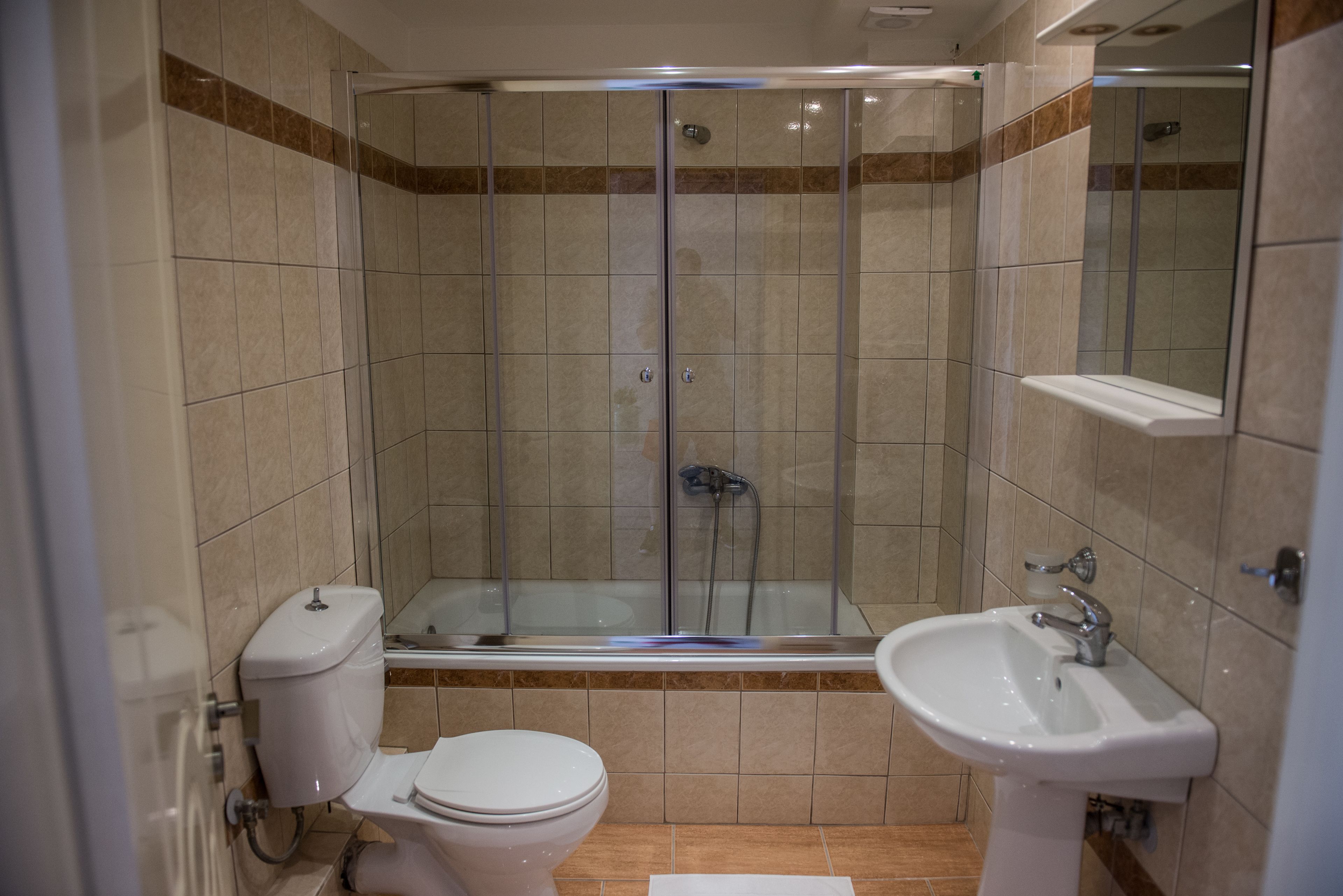 Une salle de bain avec une douche à parois de verre, des toilettes et un lavabo.