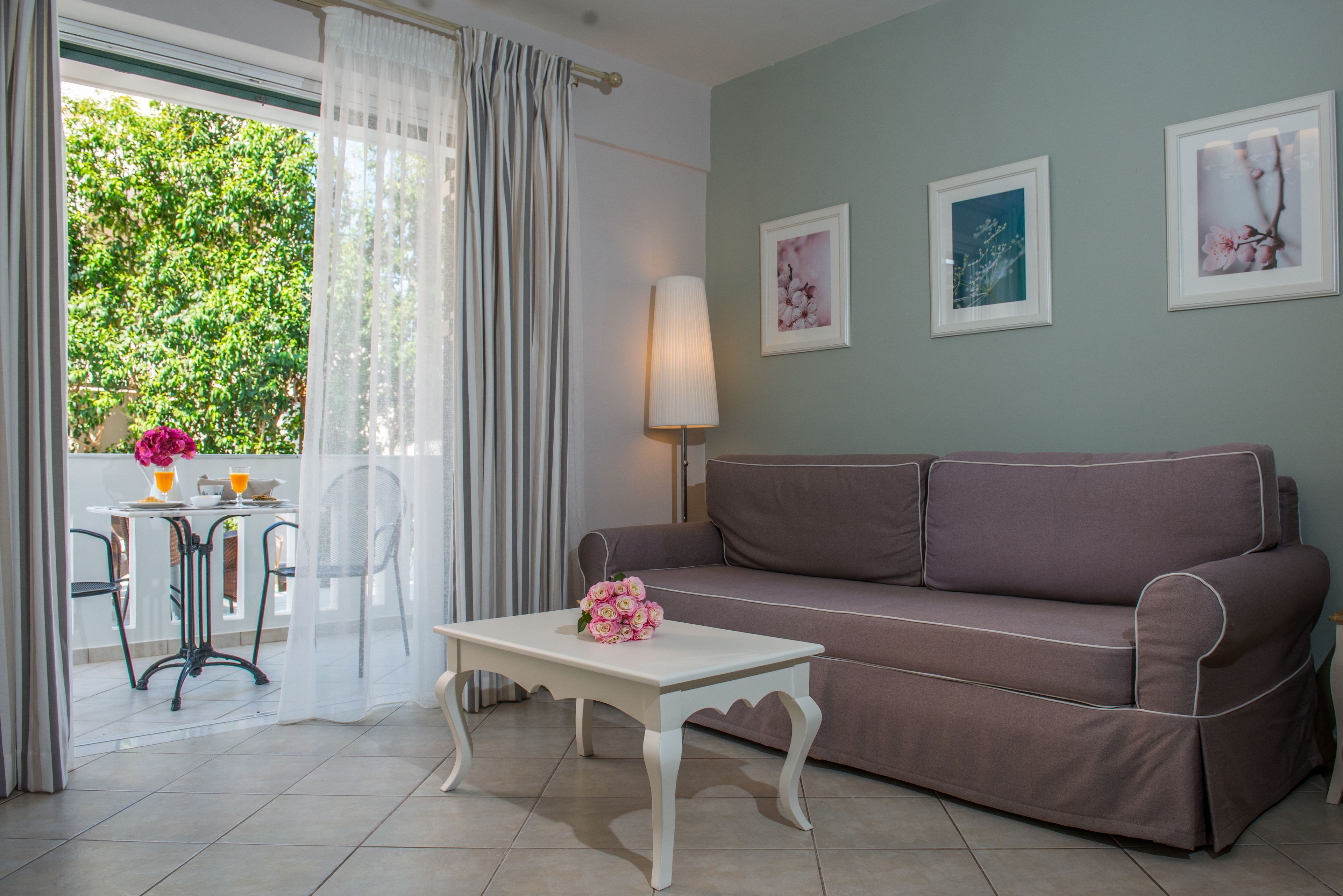 Un salón con un sofá, una mesa con un jarrón de flores y dos cuadros en la pared.