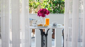 A table with breakfast items, a vase with flowers, and a glass of orange juice. - Lefkadio (Lefkada)