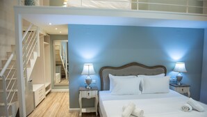 A hotel room with a bed, two bedside lamps, a nightstand, a wooden staircase, and a mirror. - Lefkadio (Lefkada)