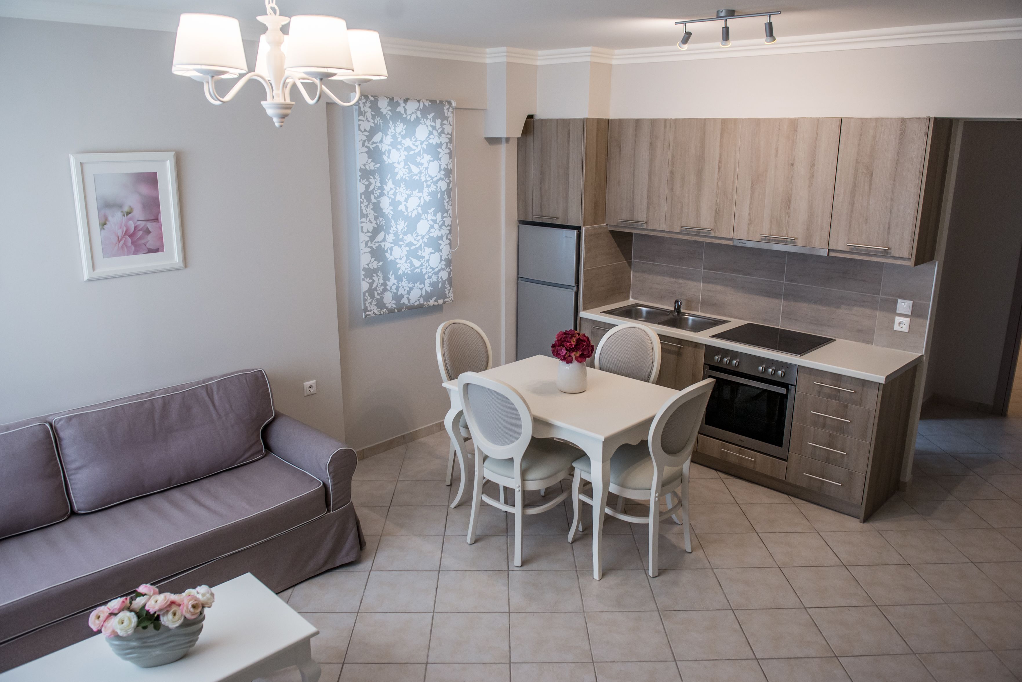 A modern kitchen with a dining area, a sofa, and a chandelier.
