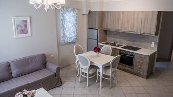 A modern kitchen with a dining area, a sofa, and a chandelier.