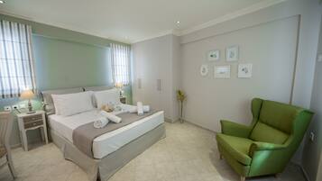 Un dormitorio con cama, mesitas de noche, un sillón verde y obras de arte colgadas en la pared.