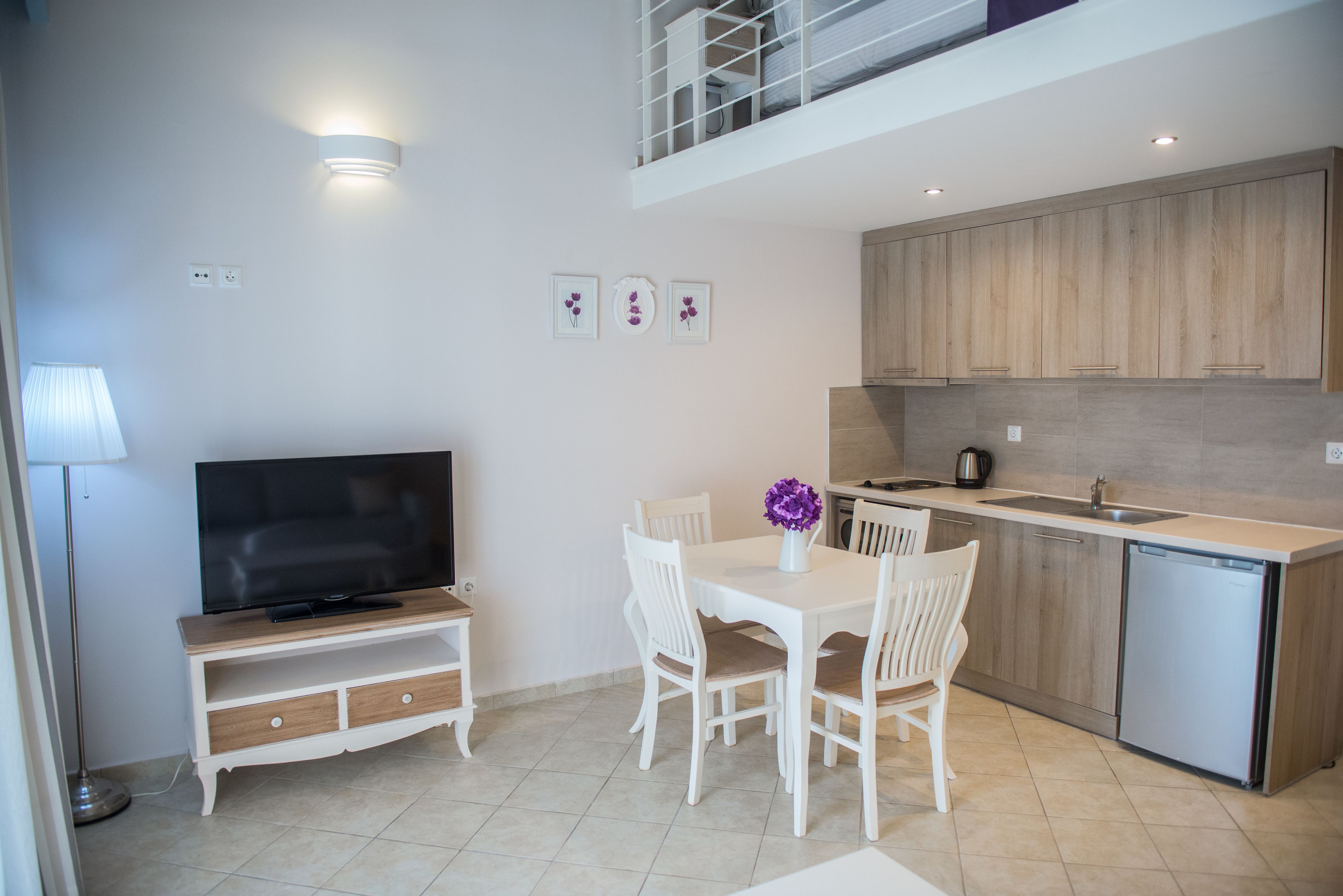 Una cocina moderna con comedor, televisor y una pequeña mesa de comedor con sillas.