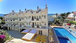 Um hotel com vários andares, varandas, piscina e áreas de estar ao ar livre.