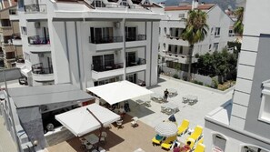 A multi-story building with balconies, outdoor seating, and a covered area with umbrellas. - Fidan Hotel & Apartment (Marmaris)