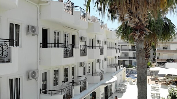 Um hotel com várias andares, varandas, unidades de ar condicionado e áreas de estar ao ar livre.