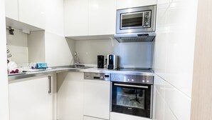 Uma cozinha moderna com armários brancos, micro-ondas embutido, máquina de lavar louça e forno.