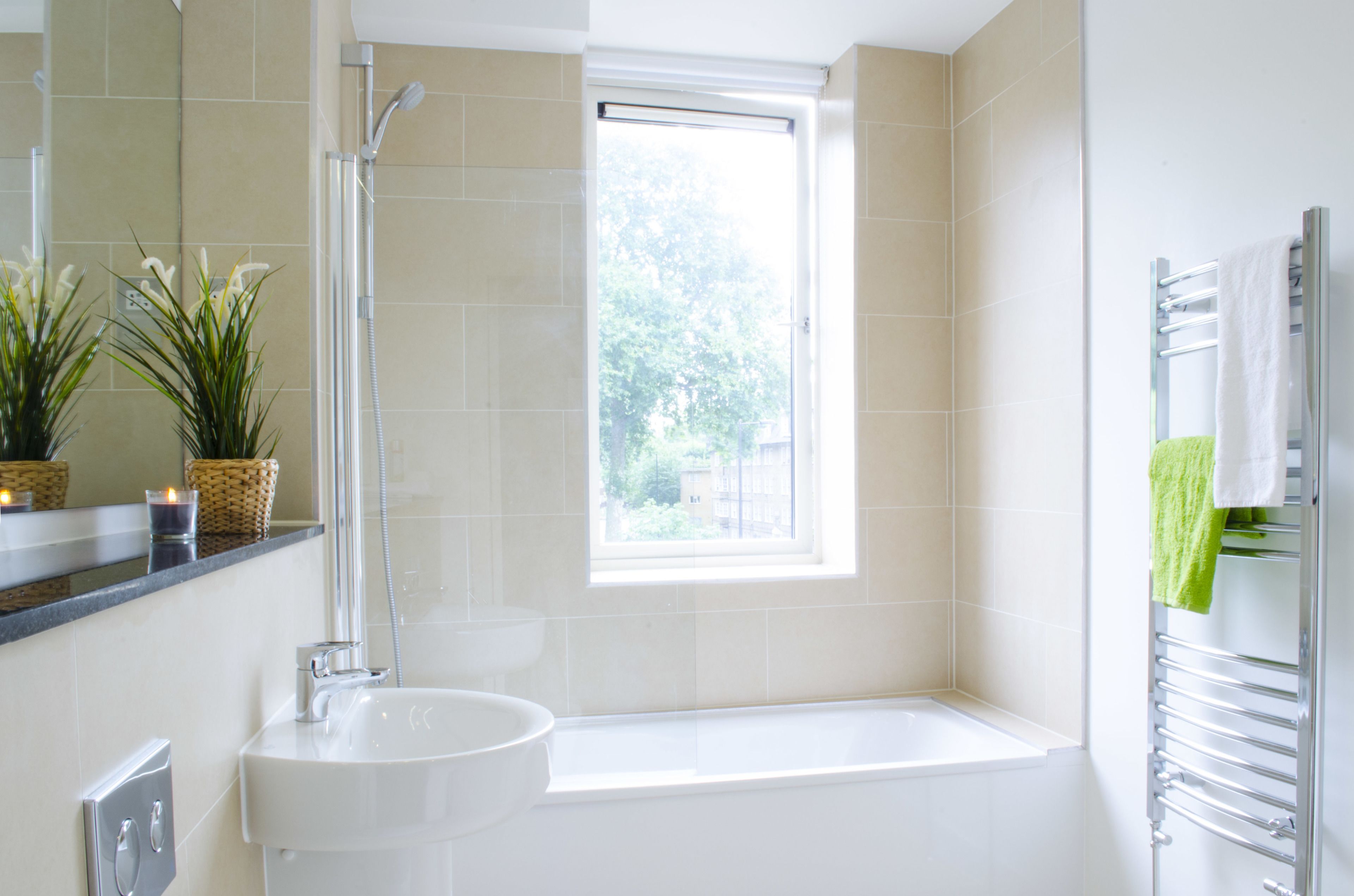 A modern bathroom with a bathtub, a sink, a shower, and a window providing natural light.