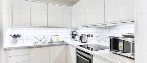A modern kitchen with white cabinets, a built-in microwave, and a dishwasher.
