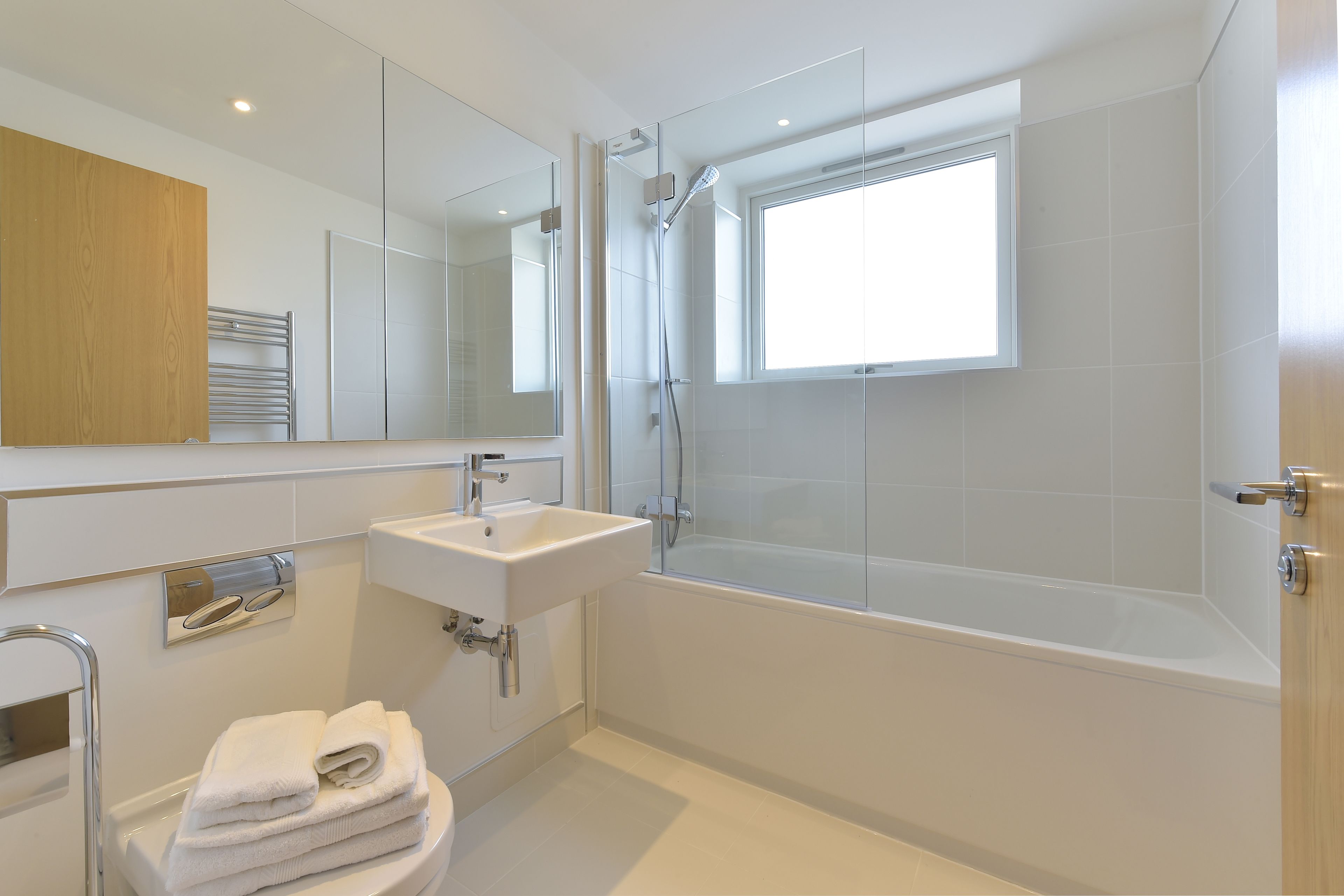 A modern bathroom with a glass-enclosed shower, a standalone sink, and a large mirror.