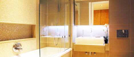 A modern bathroom with a glass-enclosed shower, two sinks, and a wooden cabinet.