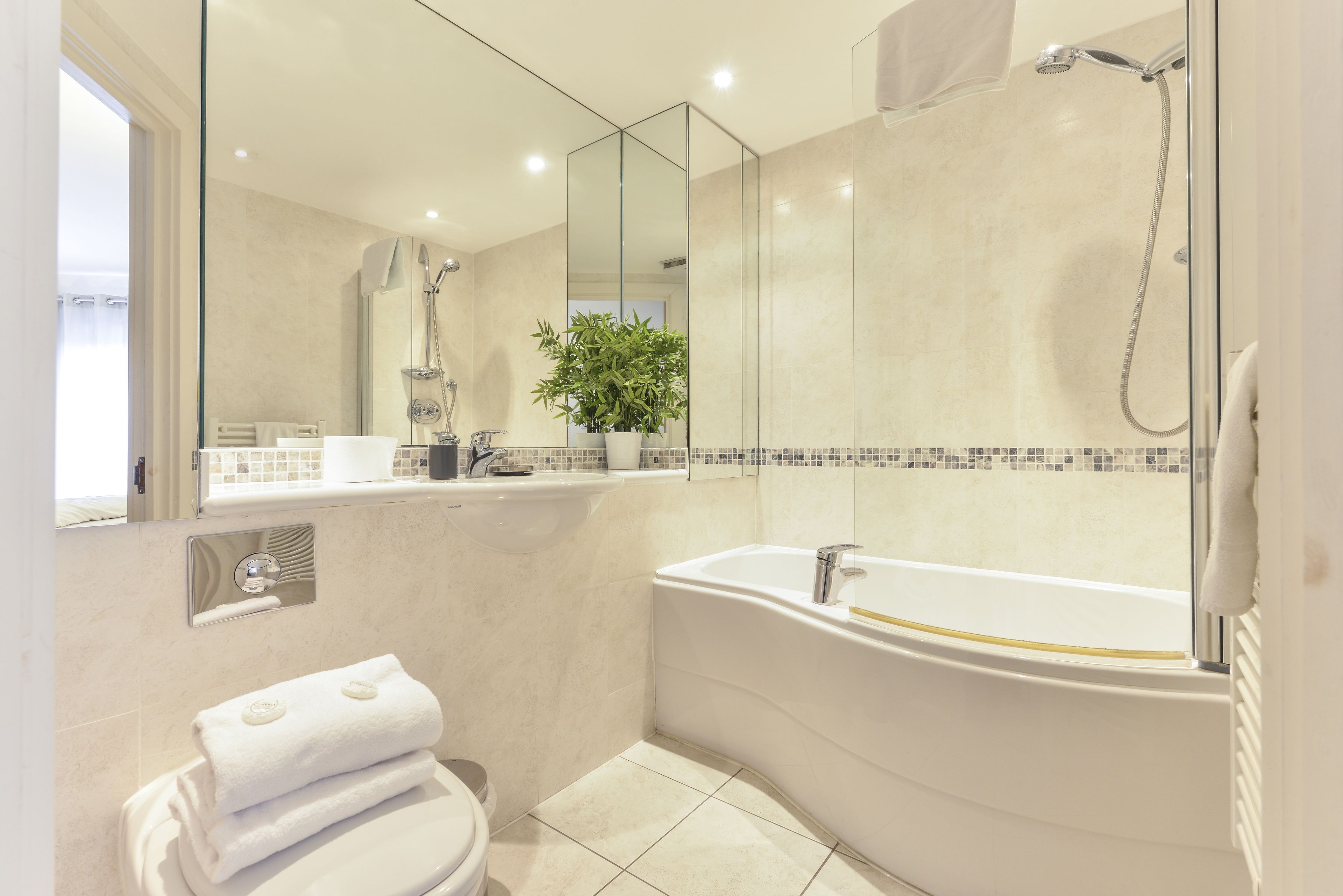 A modern bathroom with a bathtub, a toilet, a sink, and a large mirror.