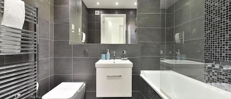 A modern bathroom with a toilet, sink, and bathtub.