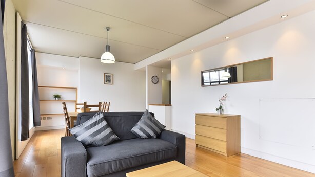 A modern living room with a grey sofa, wooden coffee table, and a wooden dresser. - Shoreditch Apartments (London)