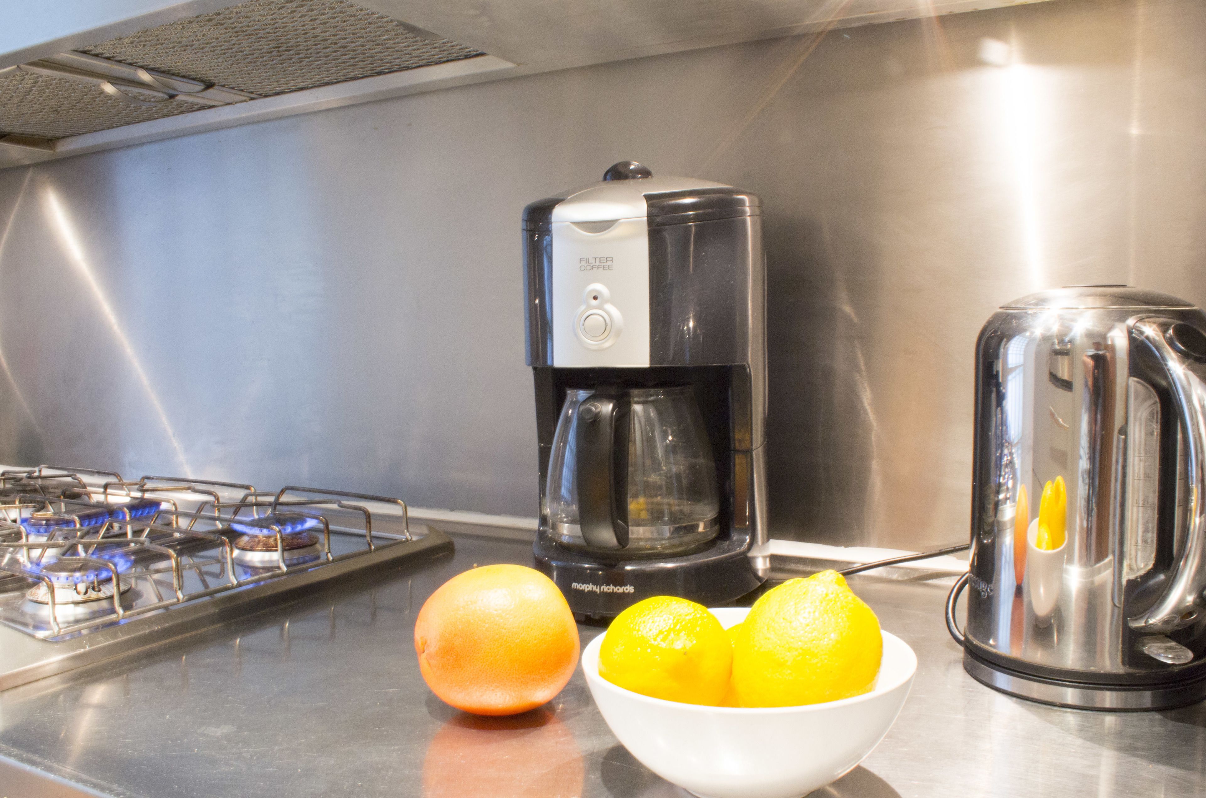 A kitchen with a gas stove, a coffee maker, and a juicer.
