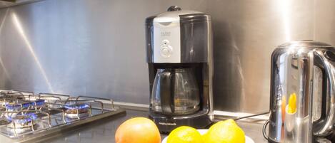 A kitchen with a gas stove, a coffee maker, and a juicer.