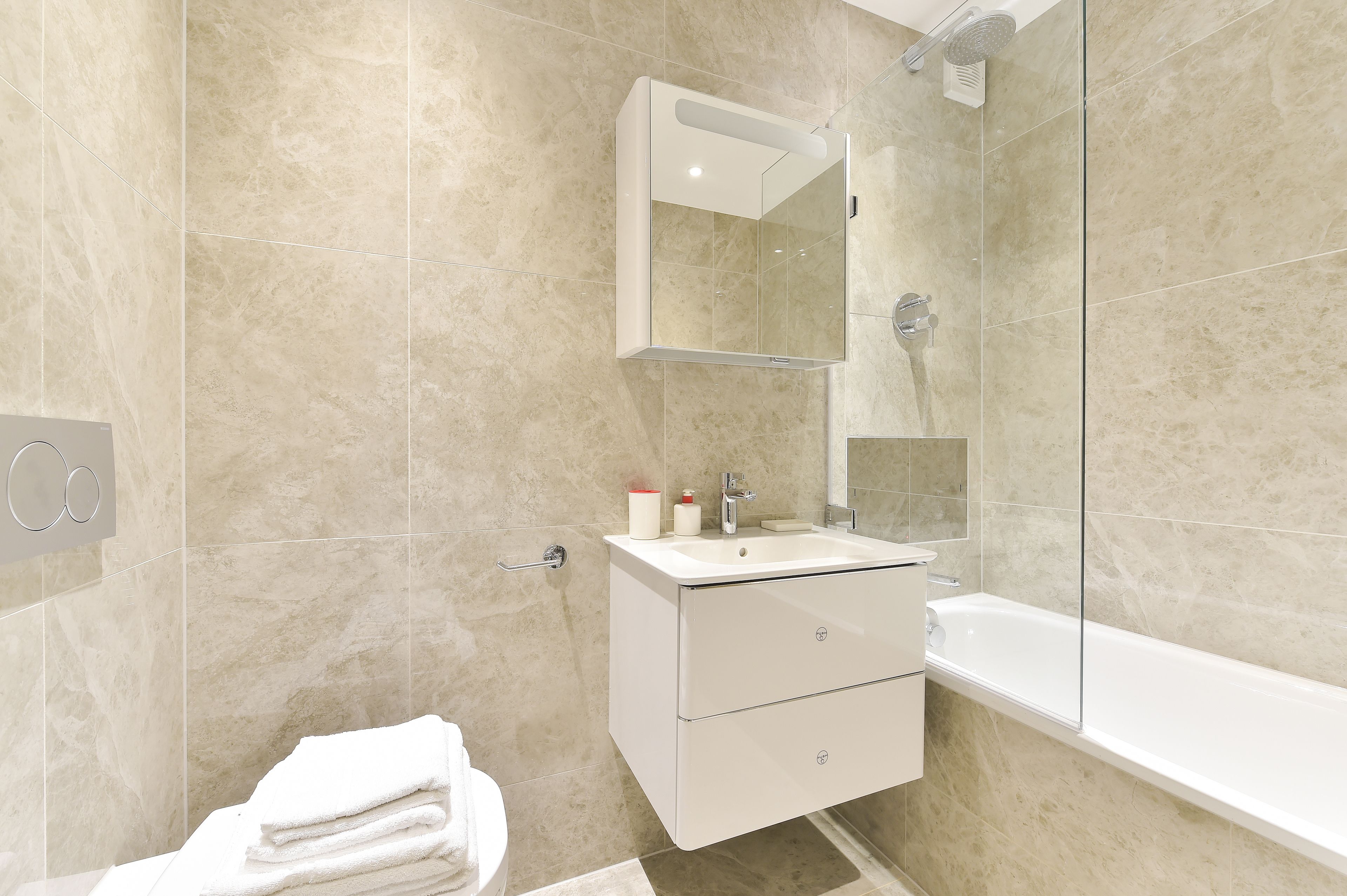 A modern bathroom with a glass shower enclosure, a white sink with a mirror above it, and a bathtub.