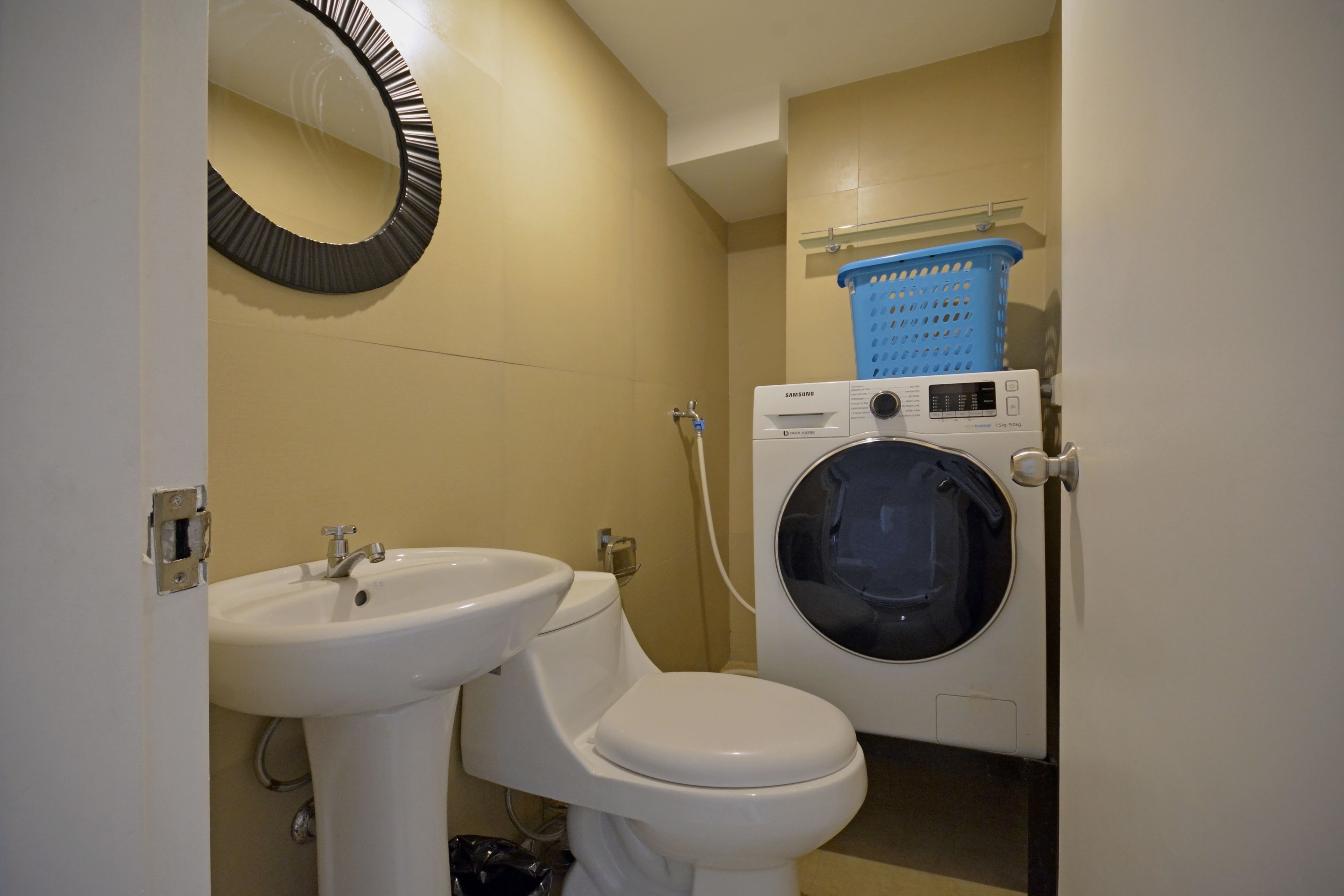 A compact bathroom with a sink, toilet, and washing machine.