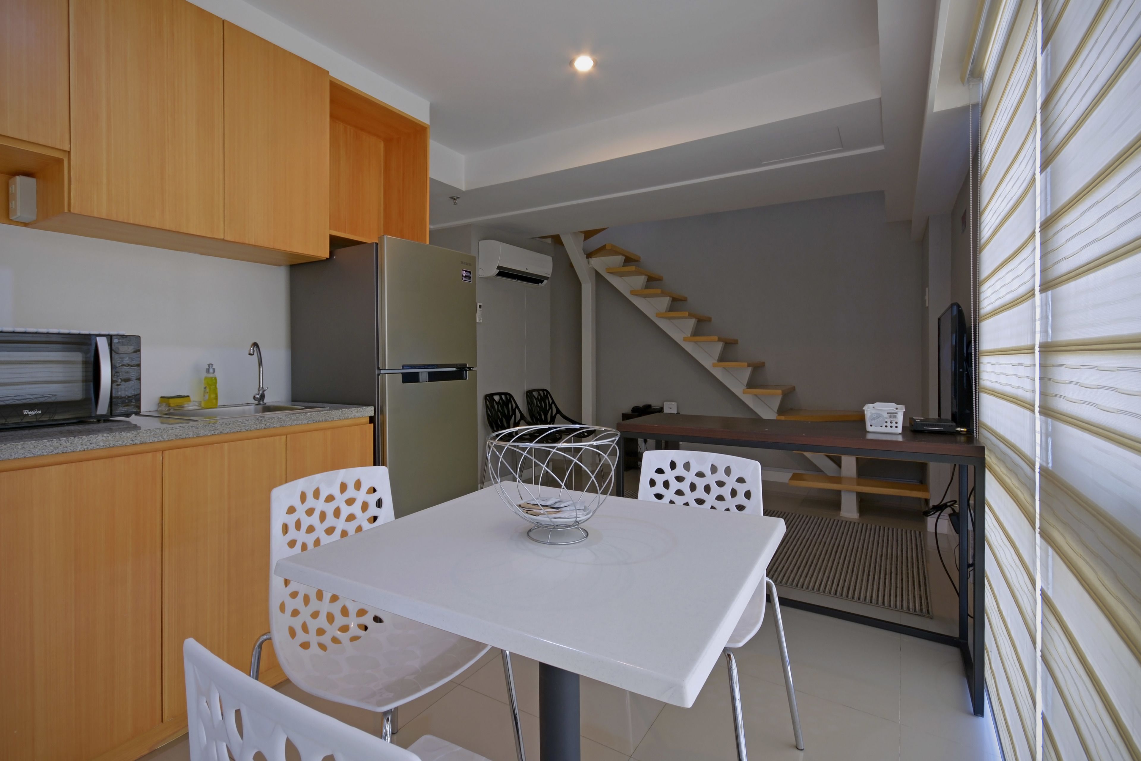 A compact kitchen with wooden cabinets, a white table, and a built-in microwave.