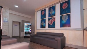 A reception area with a vending machine, a couch, and framed botanical prints on the wall. - Sagres Praia Hotel (Balneário Camboriú)