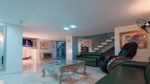 A spacious living area with a green sofa, a glass coffee table, and a staircase. - Sagres Praia Hotel (Balneário Camboriú)
