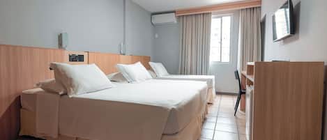 A hotel room with two beds, a desk, a TV, and a wardrobe.