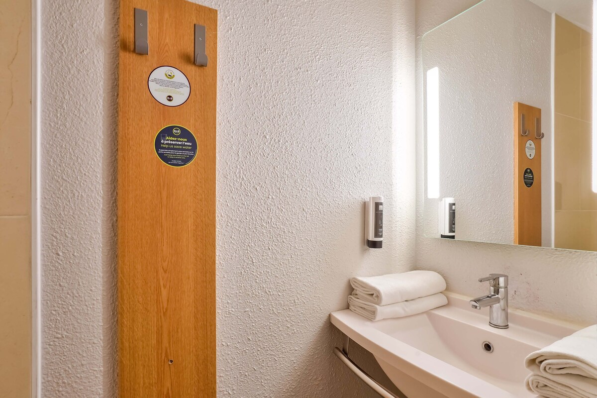 A bathroom with a wooden door, a sink with a mirror, and a towel rack.