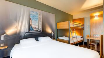Una habitación de hotel con una cama grande, una litera, un escritorio y una silla.