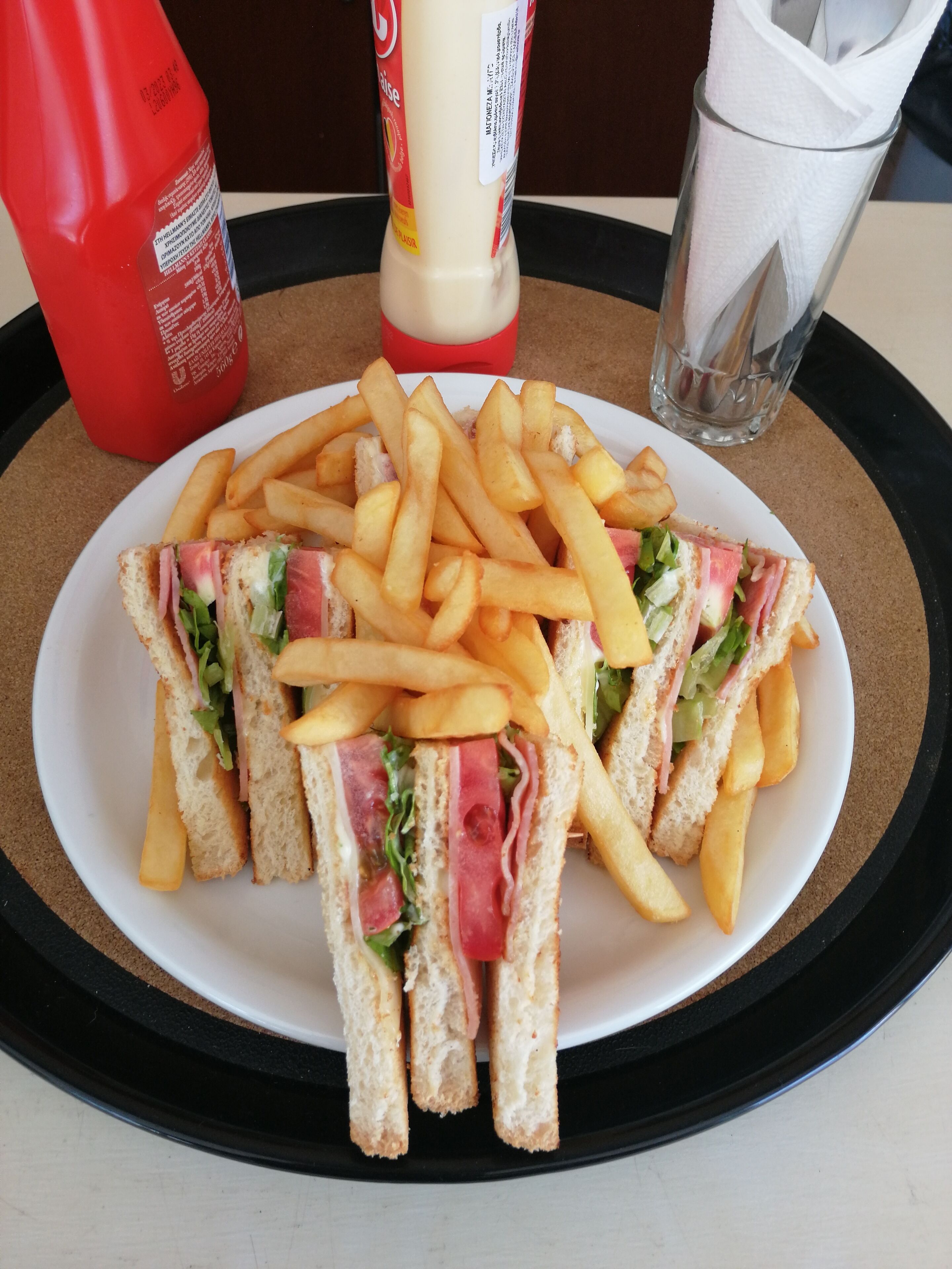 Un piatto di panini e patatine fritte su un vassoio, con salse e una bevanda.