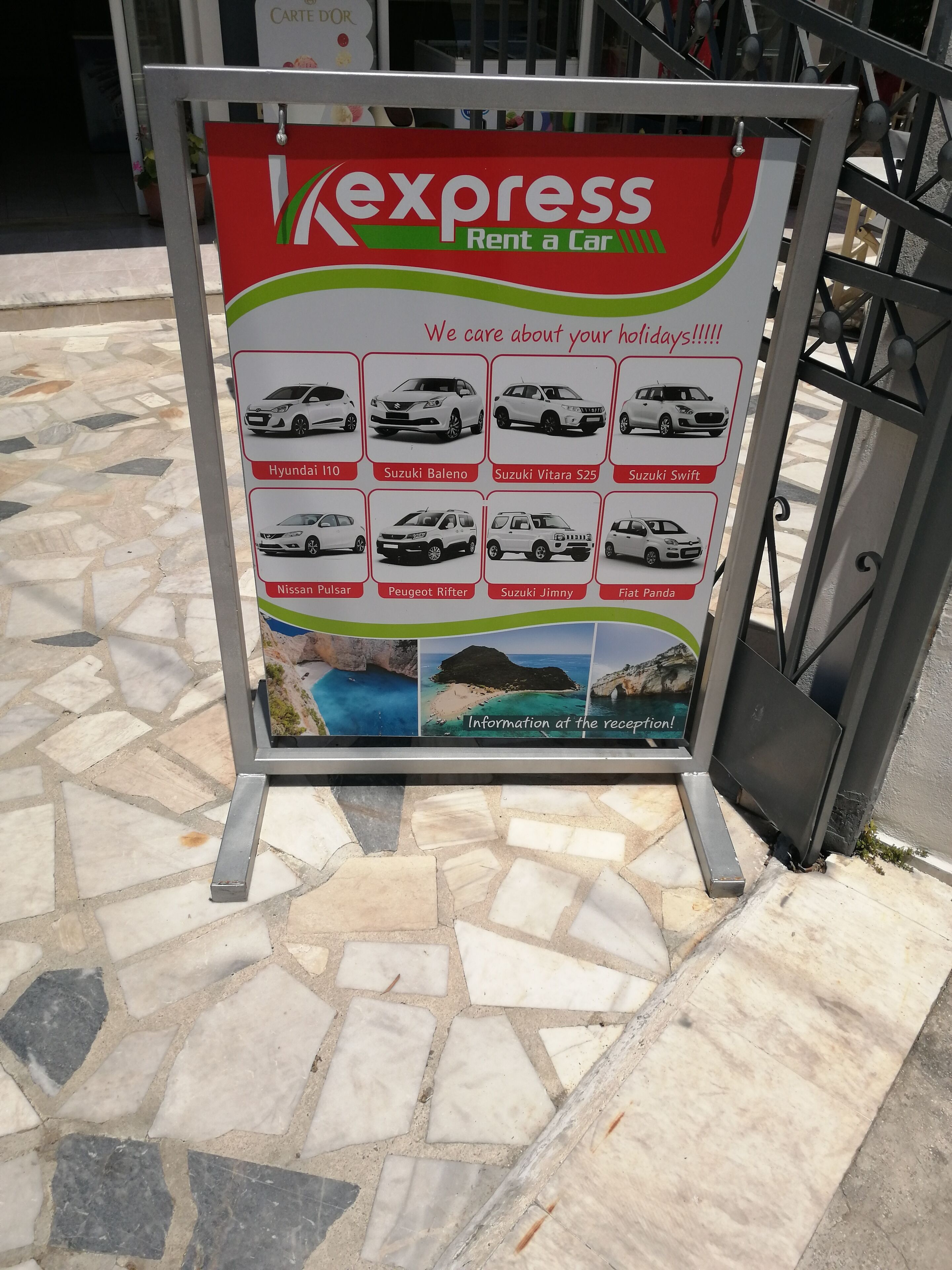 A car rental advertisement board with various car models and a scenic background.