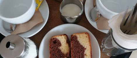 A breakfast tray with orange juice, coffee, tea, milk, sugar, and two slices of cake.