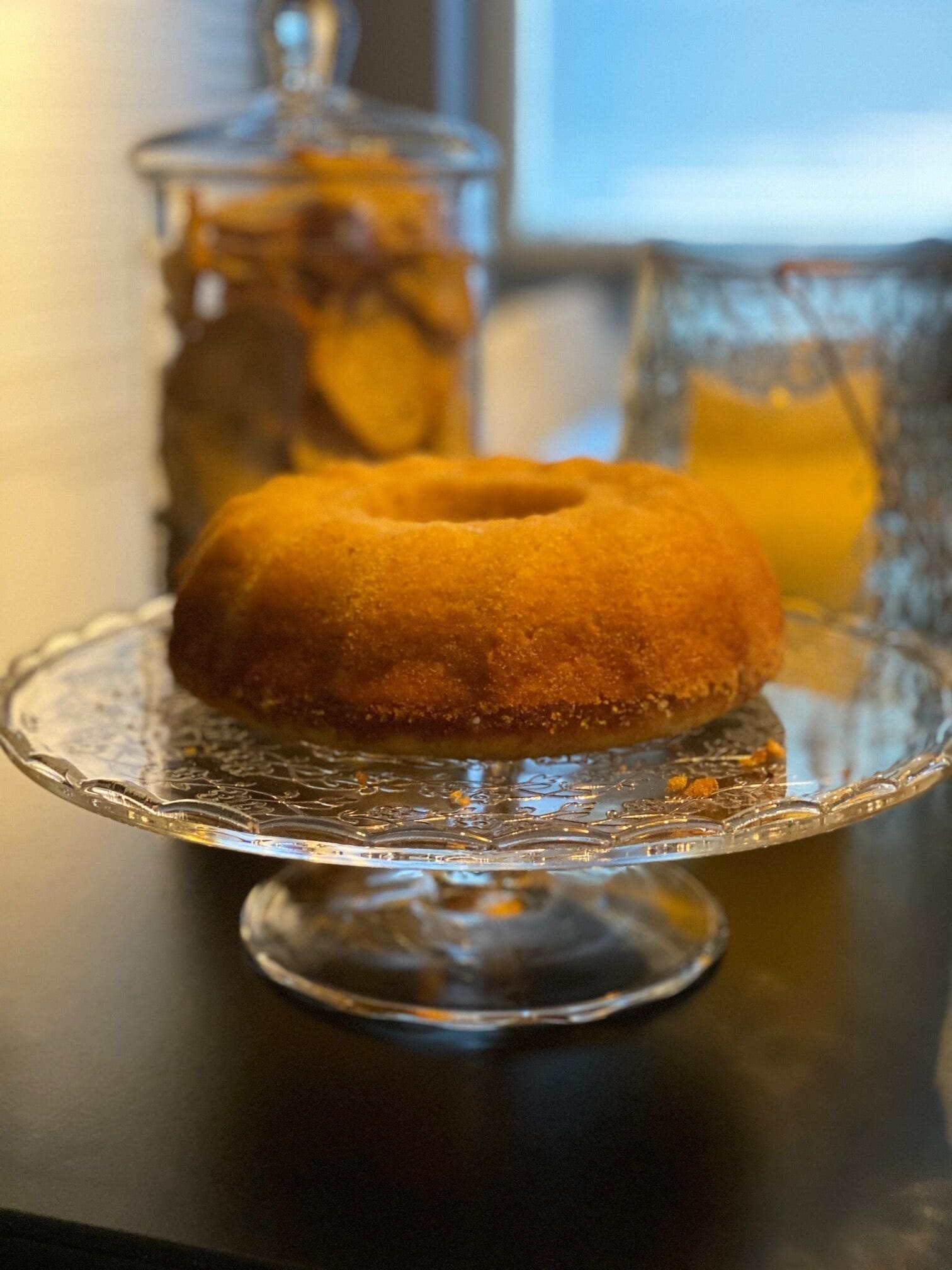 Ein glasierter Donut auf einer klaren Glasschale mit dekorativem Stiel.