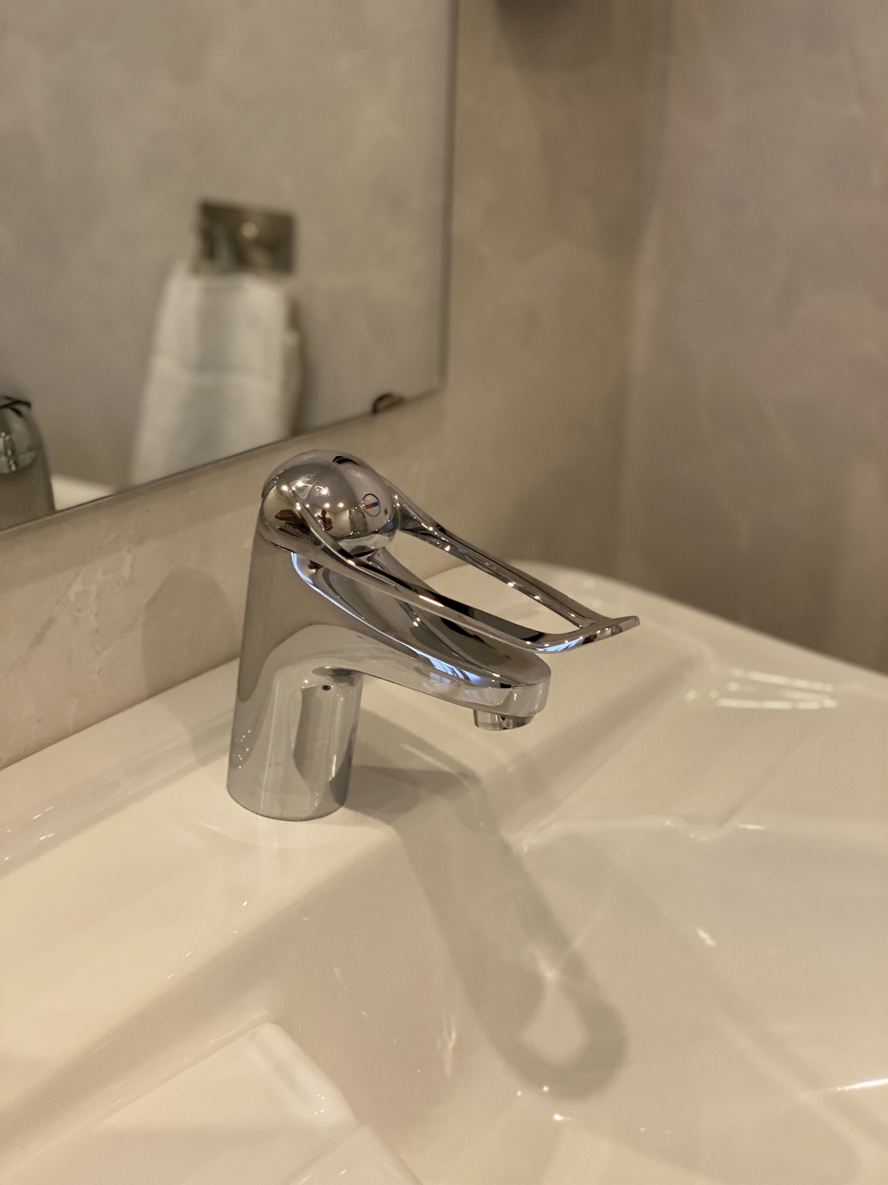 Un lavabo de bany amb un aixeta cromada i un mirall a sobre.
