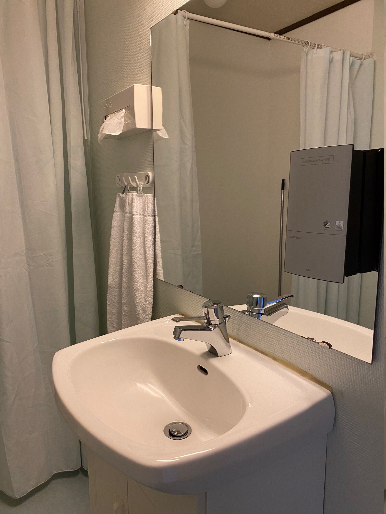 A bathroom with a white sink, a mirror, and a towel hanging on a rack.